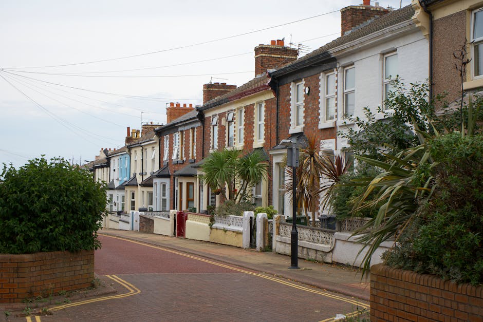 A row of traditional terraced houses with brick facades and bay windows, each featuring white window frames and decorative architraves. Some houses have small front gardens enclosed by low brick walls